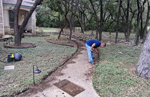 Crew member setting up landscape lighting along a front yard walkway