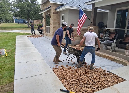 Crew hauling rock by wheelbarrow to fill a new front yard bed